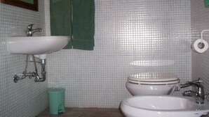 Ein Badezimmer mit zwei Waschbecken, einer Toilette, einem Spiegel und einem Mülleimer.