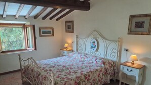 Een slaapkamer met een bed, twee nachtkastjes, een raam en een plafond met houten balken.