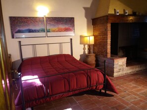 Een slaapkamer met een bed, een open haard en twee schilderijen aan de muur.