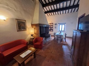 Una sala acogedora con chimenea, un sofá rojo, una mesa de madera y un comedor con sillas.