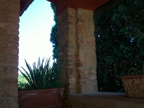 A stone archway with a view of greenery and a potted plant. - Podere Il Caggio Appartements (San Gimignano)