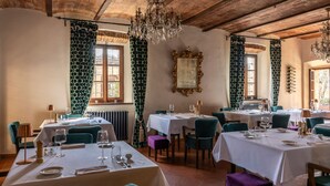 Un restaurante con mesas dispuestas para comer, una araña y cortinas estampadas.