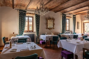 A restaurant with tables set for dining, a chandelier, and patterned curtains. - Castello di Tornano (Gaiole in Chianti)