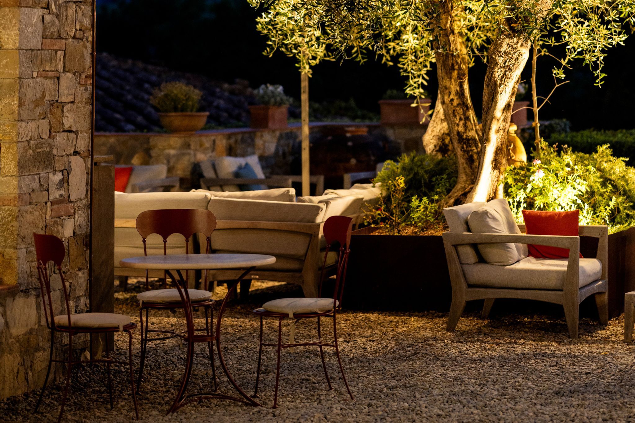 An outdoor seating area with stone walls, a table, and chairs.