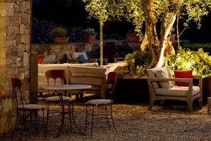 An outdoor seating area with stone walls, a table, and chairs. - Castello di Tornano (Gaiole in Chianti)
