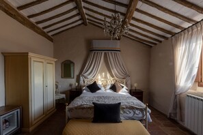 A bedroom with a canopy bed, wooden beams, a chandelier, a wardrobe, and a bedside table. - Castello di Tornano (Gaiole in Chianti)