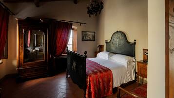 A bedroom with a wooden bed, a wooden wardrobe, a red chair, and a wooden floor.