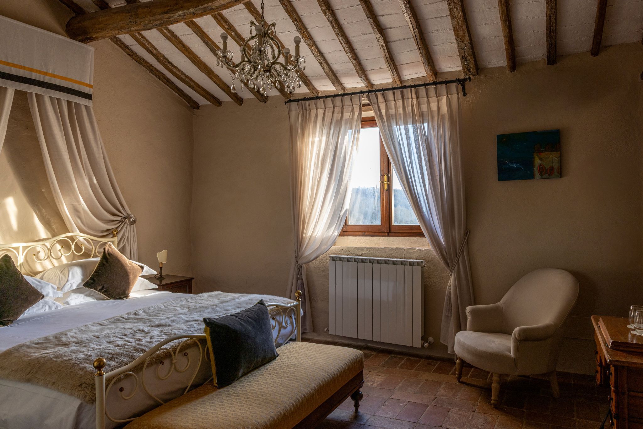 Een slaapkamer met een bed, een stoel, een radiator en een raam met gordijnen.