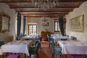 Un comedor con mesas dispuestas para el servicio, una araña y obras de arte en las paredes.