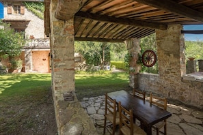 Un patio al aire libre con suelo de piedra, una mesa de madera y sillas.