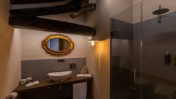Een badkamer met een houten wastafelmeubel, een grote spiegel, een rond wastafel en een douche met glazen wanden.