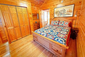 Ein Zimmer mit Holzboden, einem Bett, einem Kleiderschrank und einem Bild an der Wand.