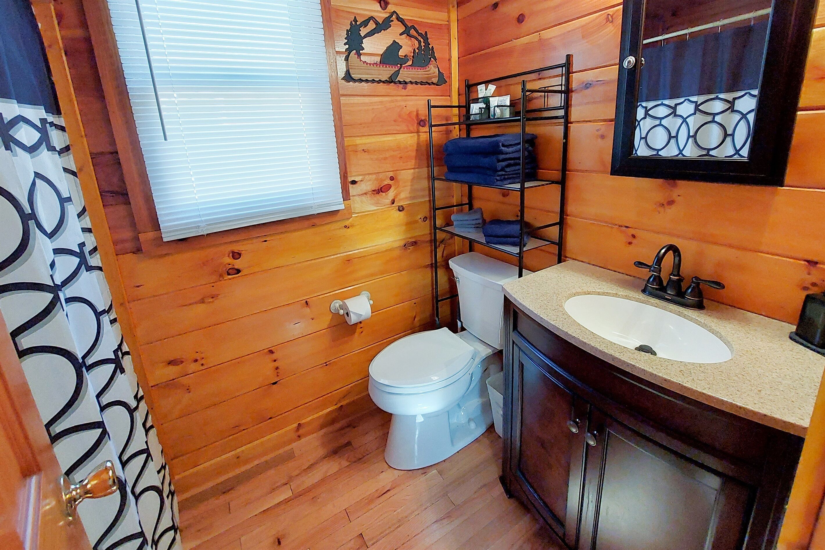 A wooden cabin bathroom with a toilet, sink, and a shelf with towels.