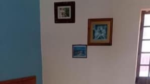 Una habitación con dos camas, cabecera de madera, una mesita pequeña y una lámpara fijada a la pared.