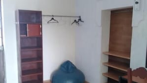 Una habitación con piso de madera, un sillón de pelota azul, un mueble de madera y un perchero con colgadores.