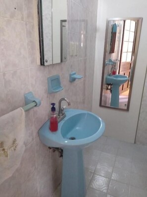 A bathroom with a blue sink, a mirror, and a towel rack. - Hostal Don Felipe  (Guadalajara)