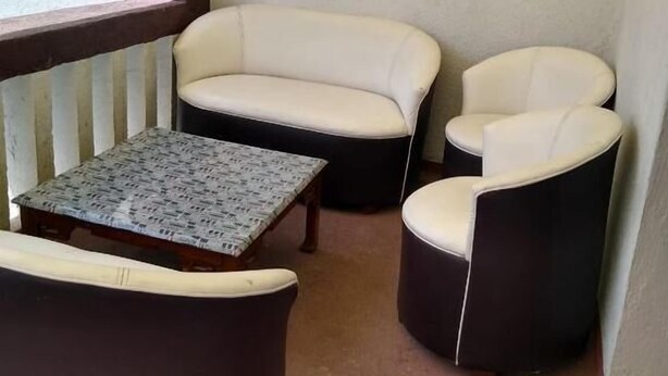 Un rincón amoblado con un banco acolchado, dos sillones y una mesita con mantel estampado.