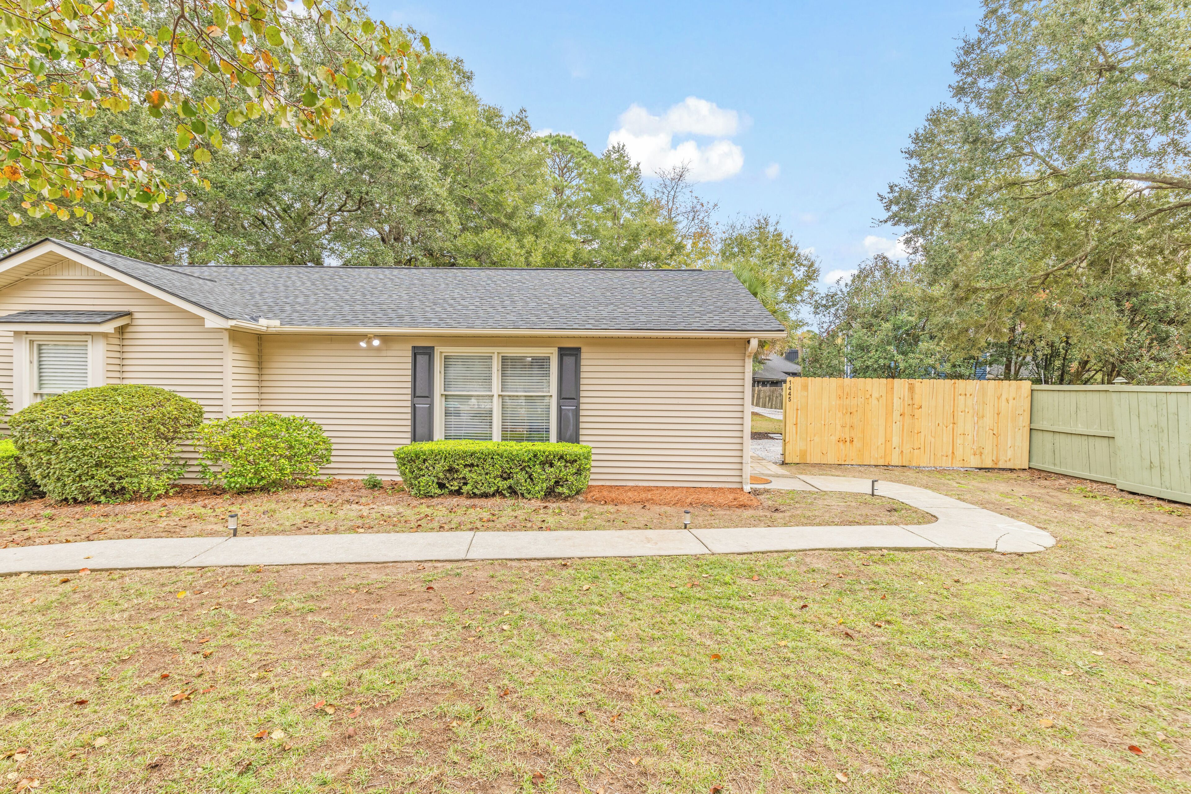 A single-story house with a front yard, a wooden fence, and a well-maintained lawn.