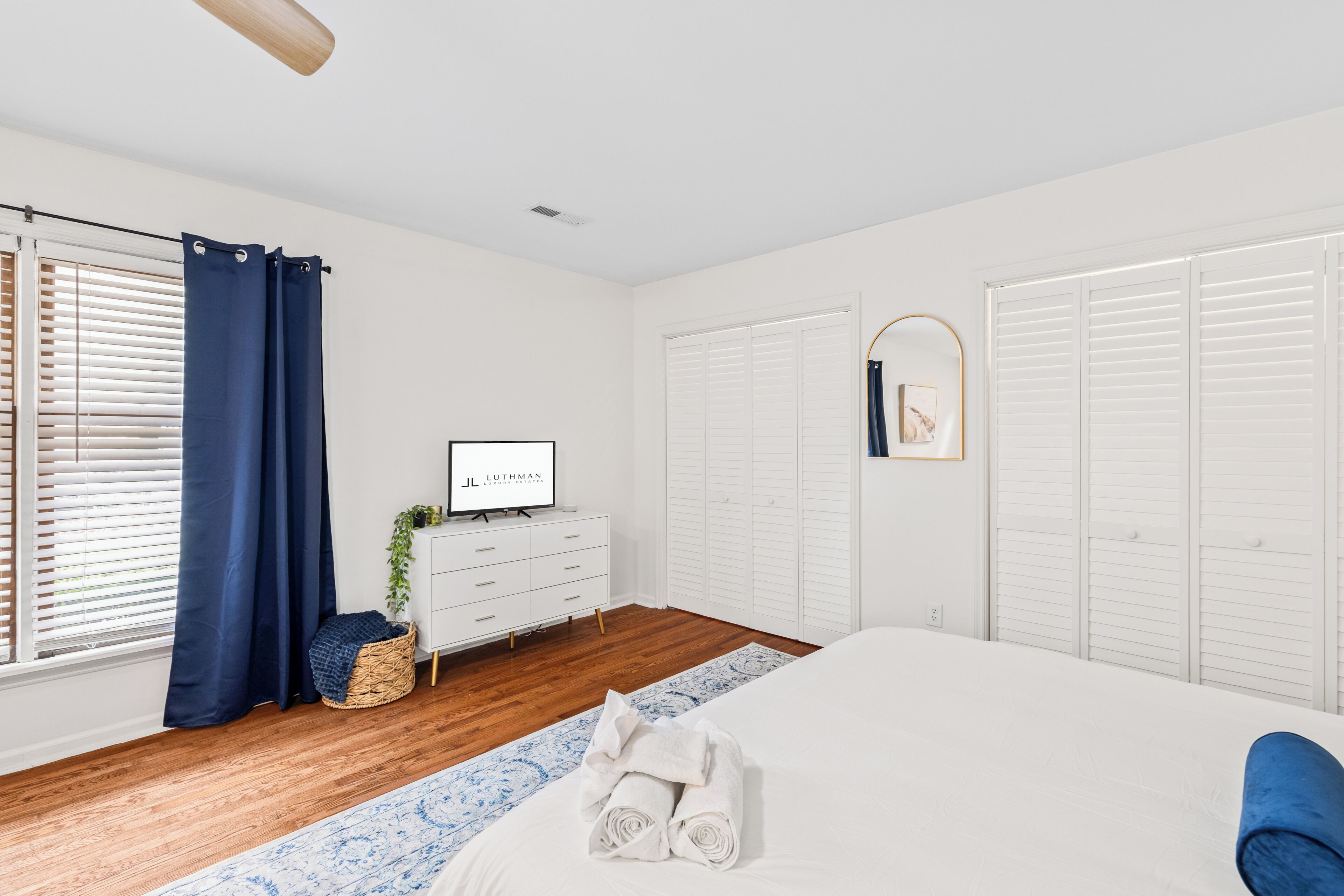 Un dormitorio con una cama, un aparador, un televisor y un armario.