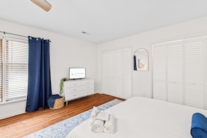 Un dormitorio con una cama, un aparador, un televisor y un armario.