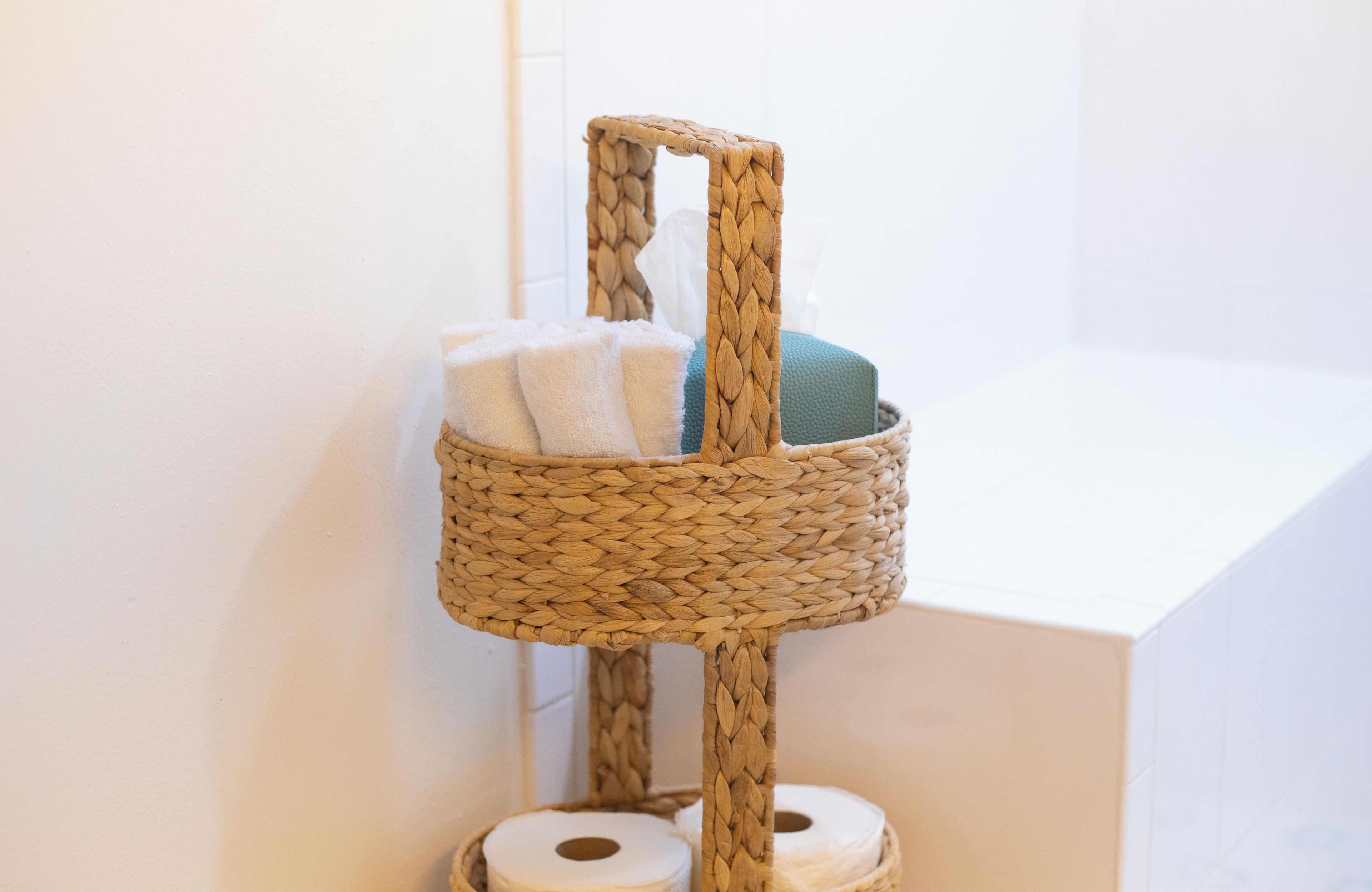 A woven cat tree with a towel and a cushion in a corner.
