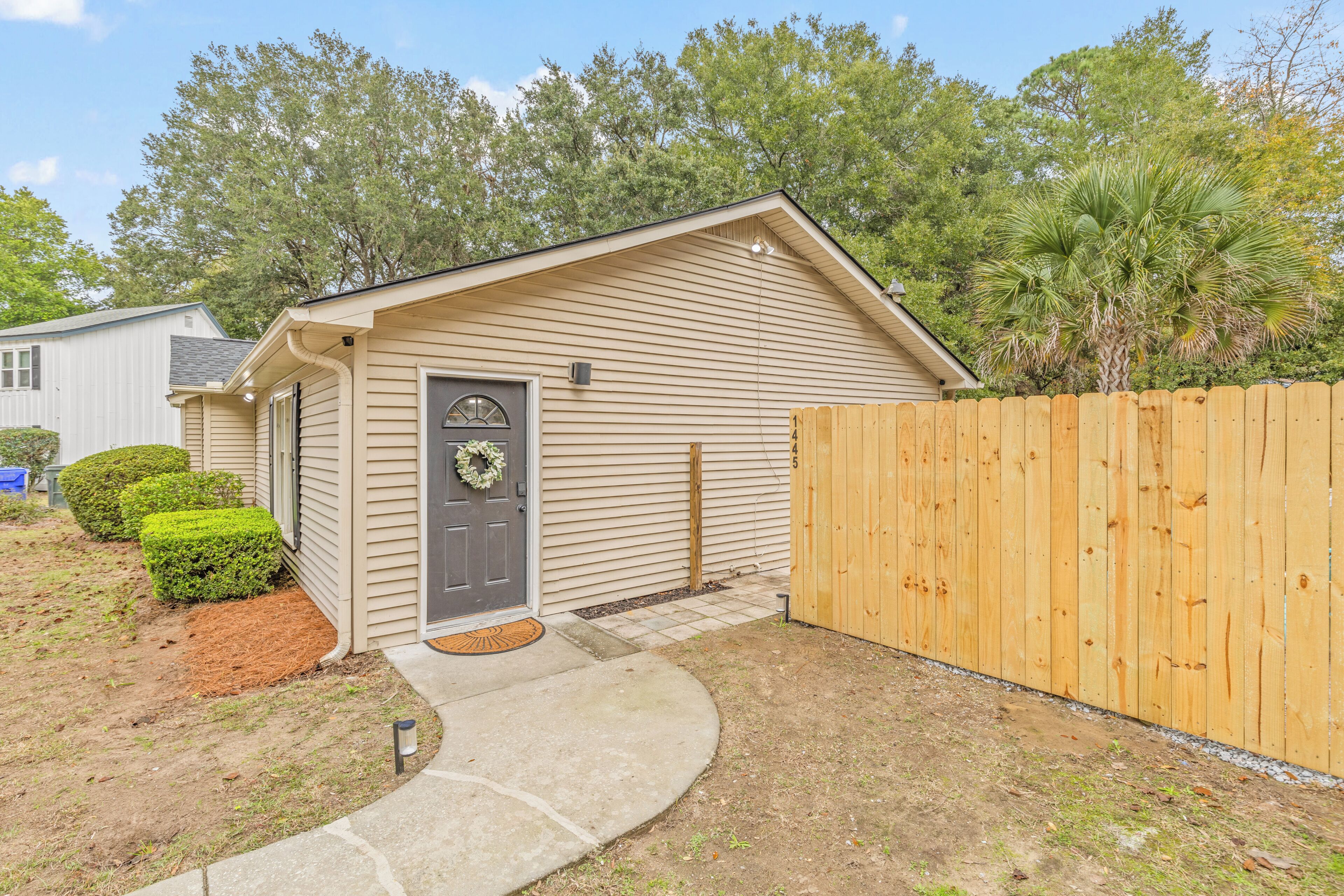 A single-story house with a front door, a small porch, and a wooden fence.