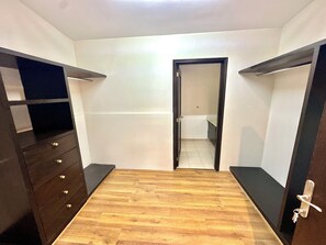 Une pièce dotée d’un plancher en bois, d’une armoire avec de nombreux tiroirs et d’une porte donnant sur une salle de bain.
