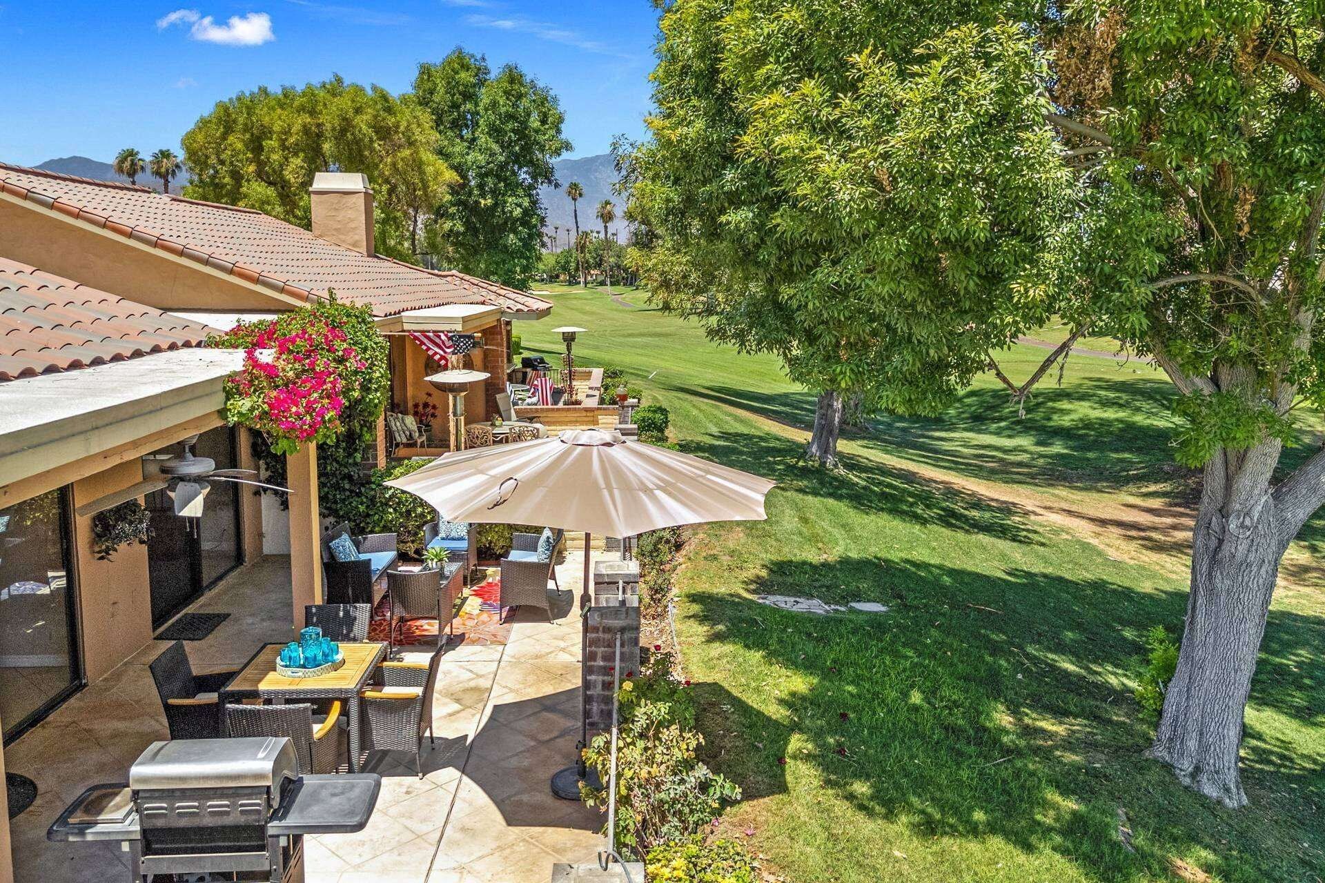 Une terrasse avec mobilier d’extérieur, un barbecue et vue sur un terrain de golf.