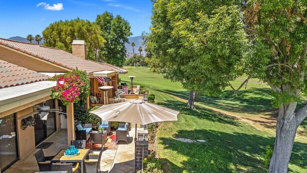 Een terras met buitenmeubilair, een barbecue en uitzicht op een golfbaan.