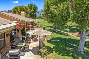 Une terrasse avec mobilier d’extérieur, un barbecue et vue sur un terrain de golf.