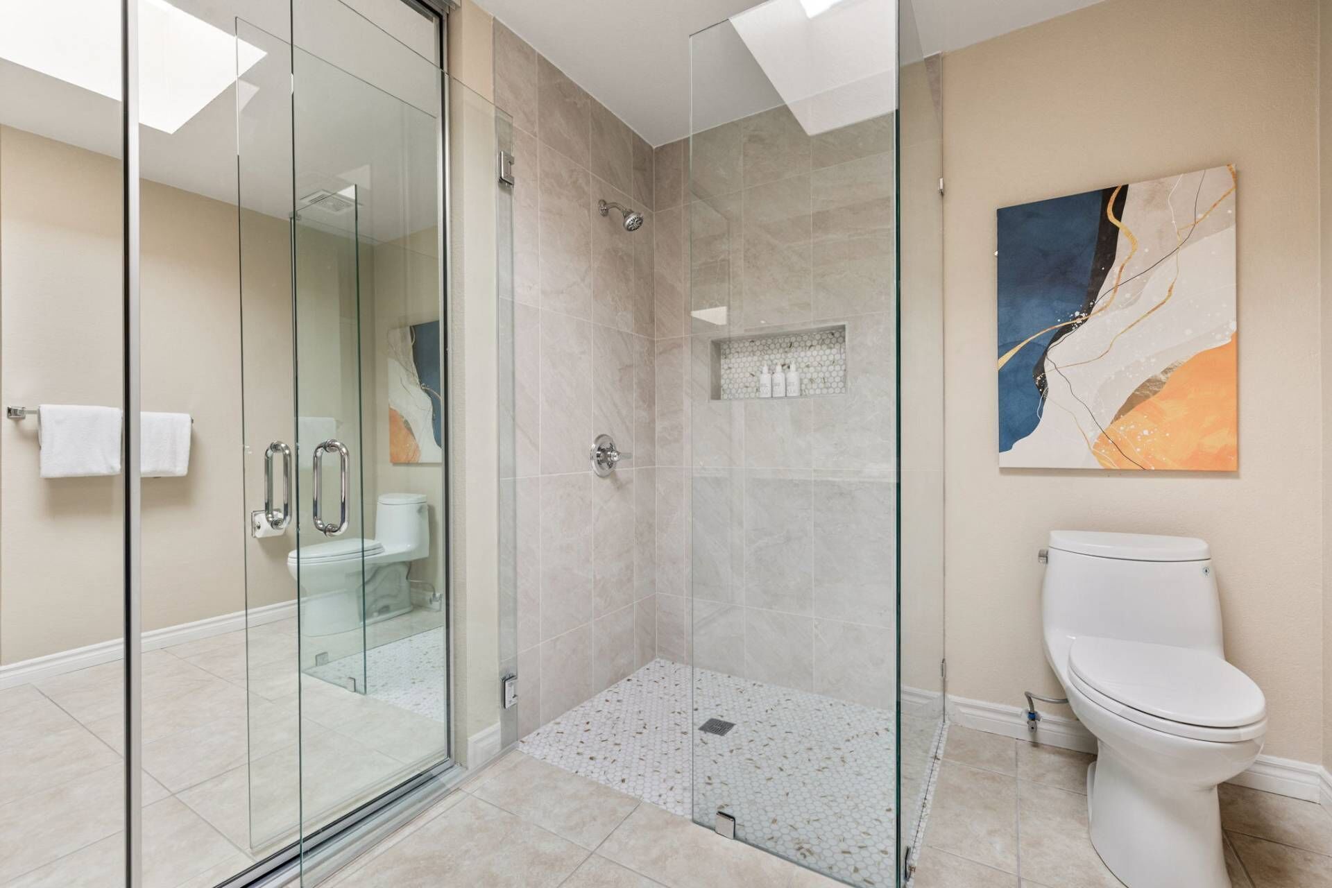 A modern bathroom with a glass-enclosed shower, a toilet, and a tiled floor.