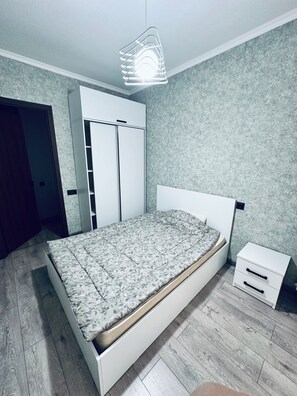 Ein Schlafzimmer mit Bett, Schrank, Nachttisch und einer Pendelleuchte.