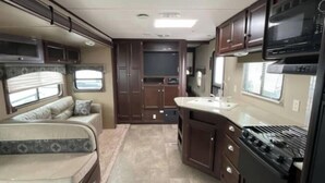 A compact RV interior with a kitchenette, a sofa bed, and a small dining area. - Spacious   recreational vehicle in Cheyenne 2 bunks two sofa beds and one master (Cheyenne)