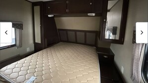 A bedroom with a bed, a window, a mirror, and built-in cabinets. - Spacious   recreational vehicle in Cheyenne 2 bunks two sofa beds and one master (Cheyenne)