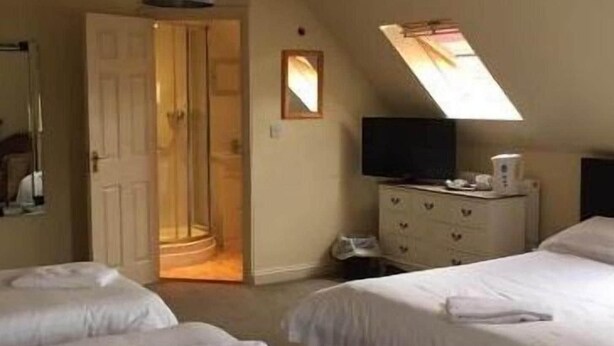 A hotel room with two beds, a desk with a computer, a mirror, and a window with a view.