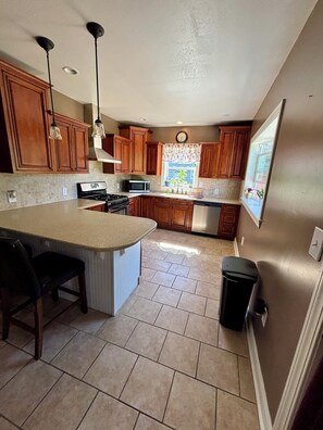 A kitchen with wooden cabinets, a stove, a microwave, and a window with a view.
