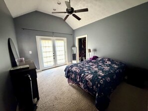 A bedroom with a bed, a dresser, a ceiling fan, and a closet.