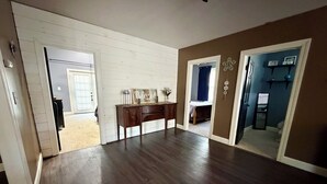 A room with a wooden floor, a desk with a sign, and a door leading to another room.