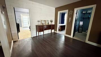 Une pièce avec un plancher en bois, un bureau sur lequel est posé un panneau, et une porte qui donne sur une autre pièce.