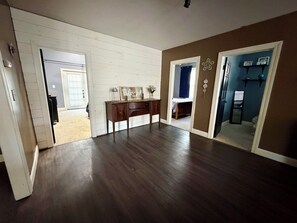 A room with a wooden floor, a desk with a sign, and a door leading to another room.