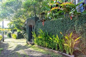 Un sendero en un jardín con seto, plantas y una estructura de piedra.