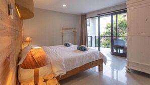 Un dormitorio con cama, lámpara, cabecero de madera, armario y balcón con vistas.