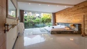 Un dormitorio moderno con una cama grande, un panel decorativo de madera, un balcón con vistas a zonas verdes y un espejo amplio.