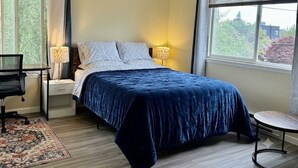 A bedroom with a bed, bedside lamps, a desk, and a chair.