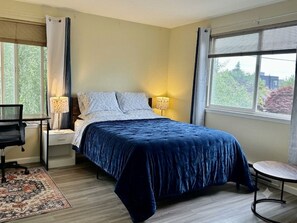 Ein Schlafzimmer mit einem Bett, Nachttischlampen, einem Schreibtisch und einem Stuhl.