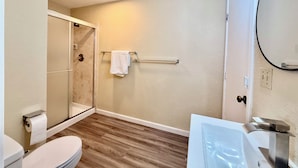 A bathroom with a toilet, a shower, a towel rack, and a mirror.