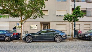 Un edificio con un'autorimessa, un albero e auto parcheggiate.
