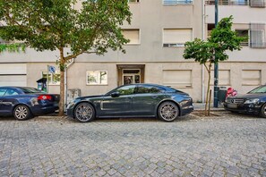 A building with a garage door, a tree, and parked cars. - Apartment 'Lovely  Matosinhos Beach' with Private Terrace, Balcony and Wi-Fi (Matosinhos)