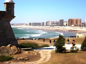 A coastal view with a lighthouse, beach, and buildings in the background. - Apartment 'Lovely  Matosinhos Beach' with Private Terrace, Balcony and Wi-Fi (Matosinhos)