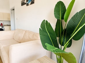 Ein Wohnzimmer mit einem beigen Sofa, einer Kaffeemaschine und einer großen Grünpflanze.